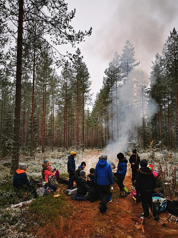 Lapset metsässä nuotion äärellä.